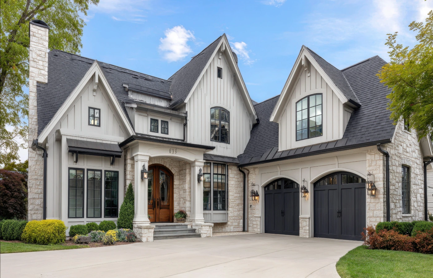 Large two-story home with stone and white siding and a two-car garage