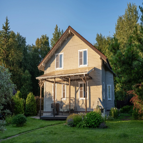 Two-story home with a front porch among tall trees