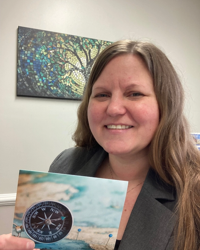 Jennifer Andrews, Realtor Shelbyville Indiana, holding a compass print in her Shelbyville office.